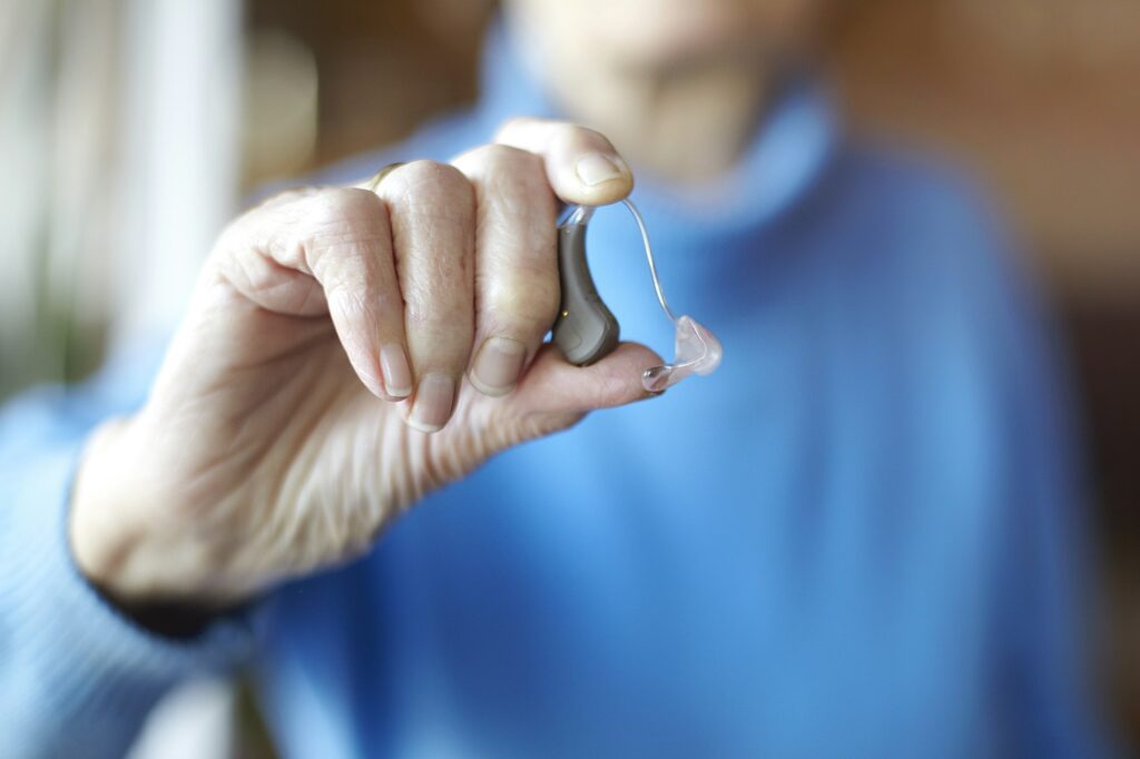 Senior woman holding hearing aid, close-up